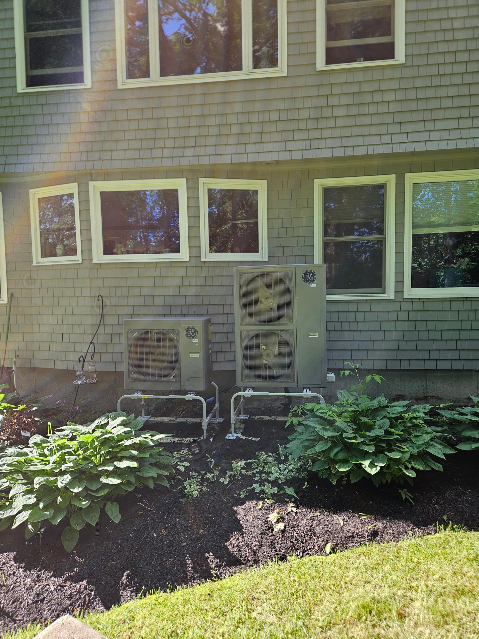 Twin high-efficiency heat pump units installed by Aces Highlands outside a Maine home